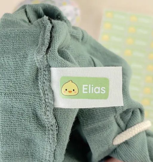 Navnelapp med navnet Elias og en kylling, sydd på en grønn genser